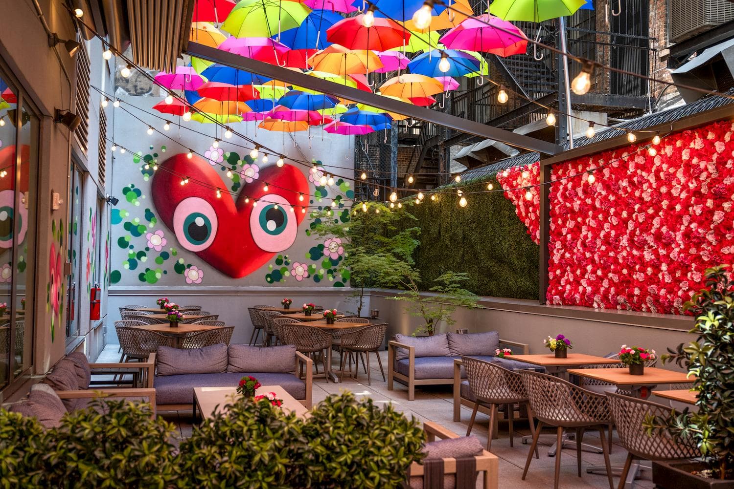 The back patio at Innside New York NoMad, canopied with coloured umbrellas and festoon lights.