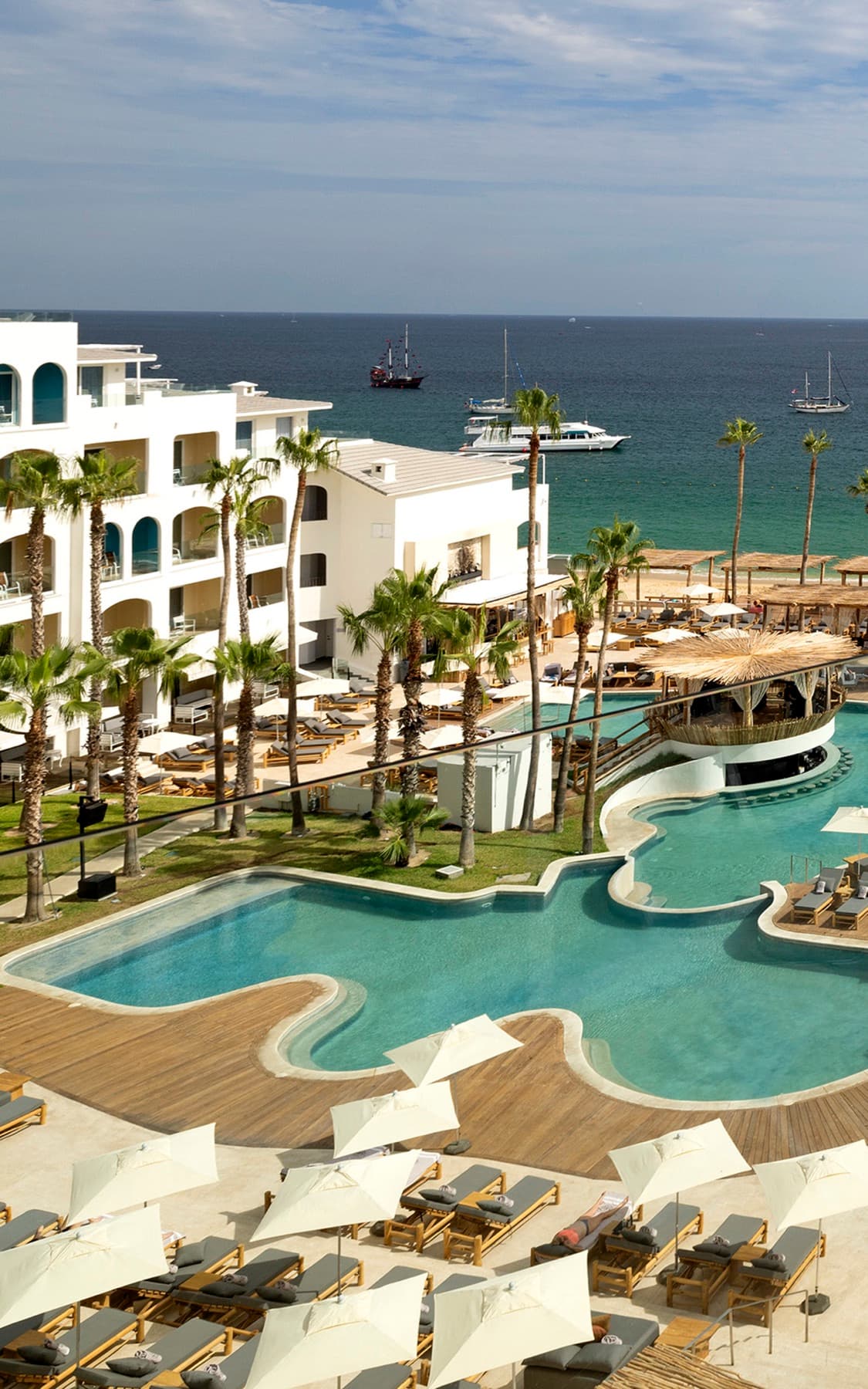 The view from a Superior ME+ room at ME Cabo, over the pool decks and beach to boats anchored in the bay.